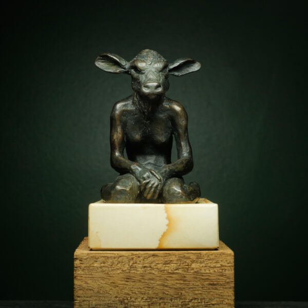This is a solid bronze, exquisitely sculpted original artwork of an imaginary female minotaur, which in greek mythology is called an 'Ariadne'. Kneeling in a contemplative pose she has the body of a young woman and the head of a calf. Created during our classes, Alice Walsh sculpted this sensitive piece which is only 6cm wide x 6cm deep x 10cm high and sits on a sandstone base which is 10cm wide x 7,5cm deep x 3,5 cm high. The whole sculpture weighs 1,2 kg and together with the base it is 13,5cm high x 7,5cm wide x 10cm deep. It has a black patina with hints of turquoise green and bronze. The edition size is only 18.  Alice  is a qualified fine artist and runs an illustration, animation and info graphic studio. You can view her work under www.fablestudio.co.za